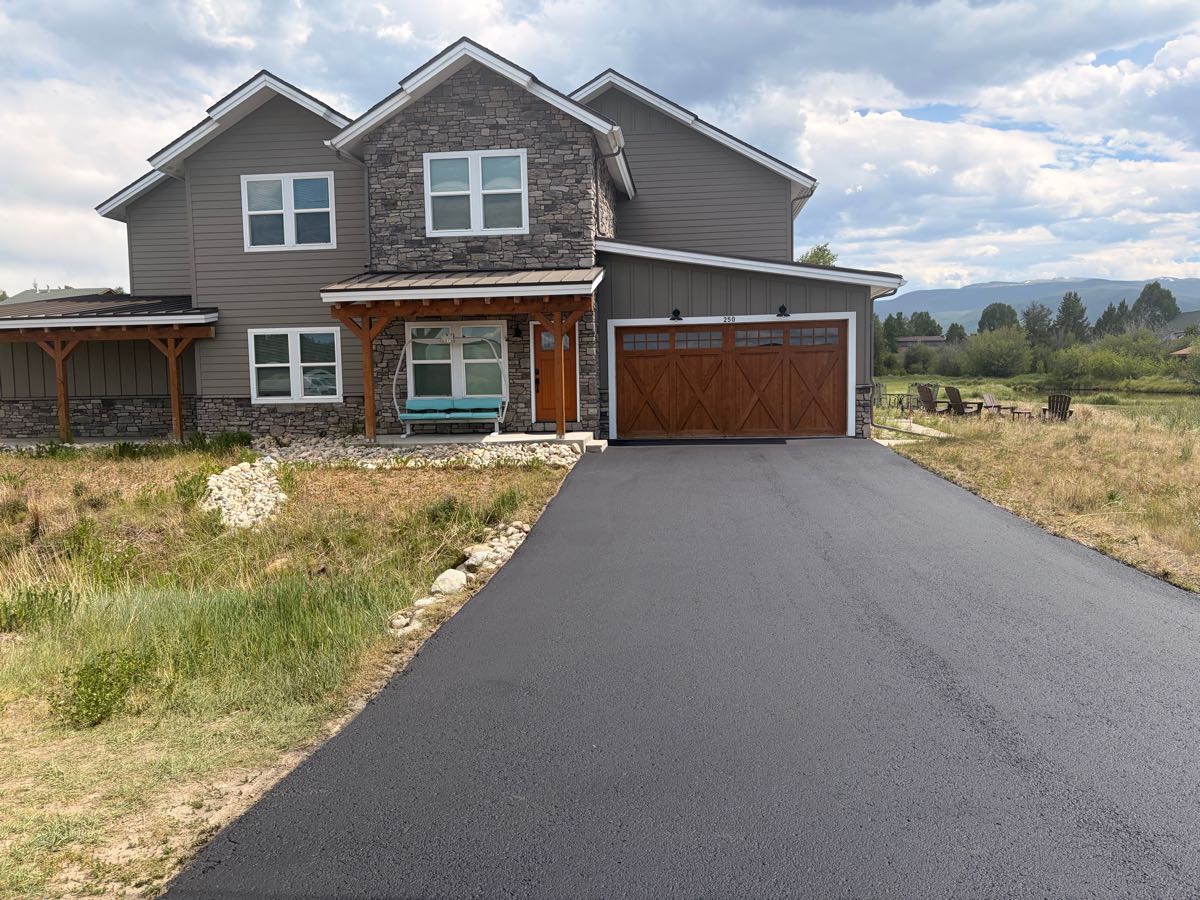 Freshly sealed driveway at a stone-and-timber mountain home — Grand County, CO